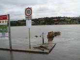 Large log at boat ramp near water height board